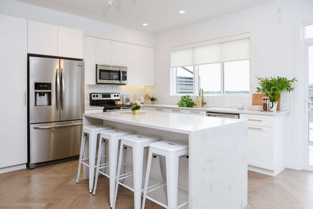White kitchen with marble countertops and white tile. Kitchen plants. Cobalt Beach Showhome in Jensen Lakes St. Albert