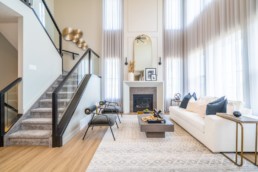 Great room in Calypso showhome Jensen Lakes. Large staircase with ceiling high windows white and grey interior modern and classy design.