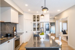 Calypso showhome in Jensen Lakes. Kitchen design with abstract grey and white counters accented with gold trimmed interior design and solver appliances.
