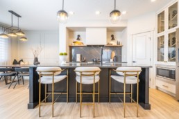 Gold trimmed kitchen with black stone countertops and gold interior modern design in St. Albert. Pacesetter Calypso showhome in Jensen Lakes.