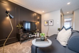 Calypso showhome loft with black wall and wire tv stand and side tables. Dark grey interior design in Jensen Lakes St. Albert.