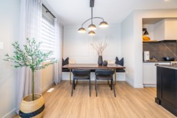 Secluded dining area with black chairs and bench seating, modern wood and black interior design in Jensen Lakes. Pacesetter homes St. Albert.
