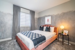 Secondary kids bedroom with abstract grey walls geometric bedding and cloth pink bedframe. Jensen Lakes Pacesetter Homes in St. Albert.