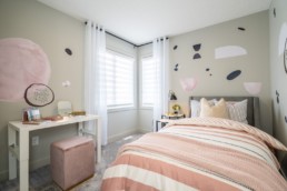 Girls bedroom with pink bed spread and pink decor accents. Located in Pacesetter showhomes in Jensen Lakes St. Albert.